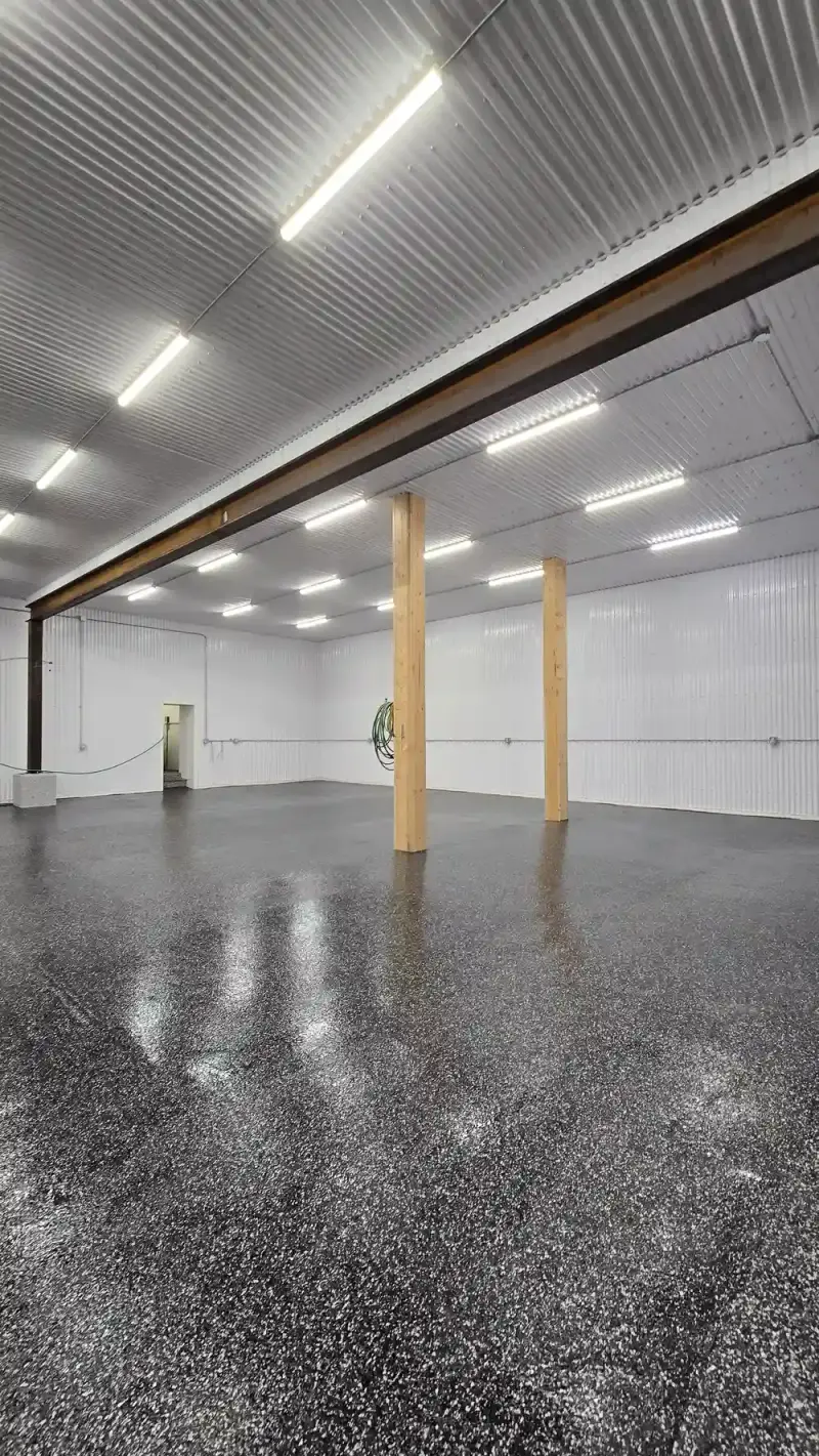 Glossy black flake floor around columns in a large shop