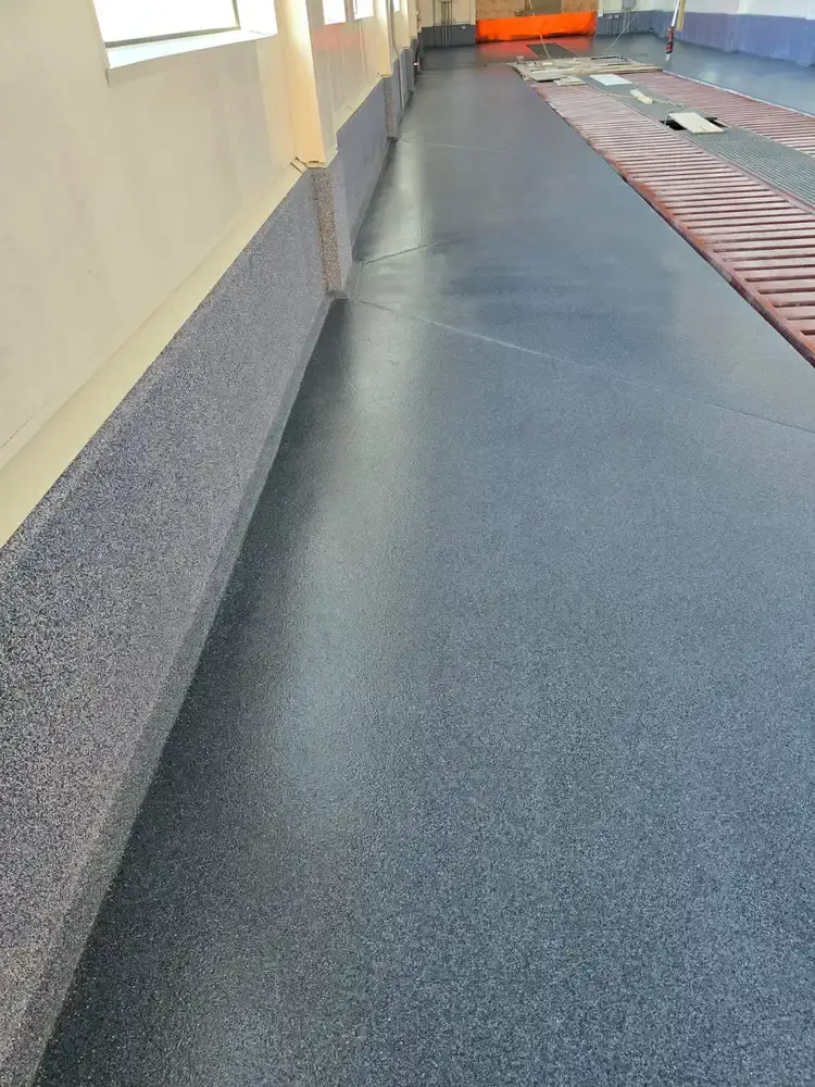 Blue flake epoxy floor and coated wall base along a car wash bay