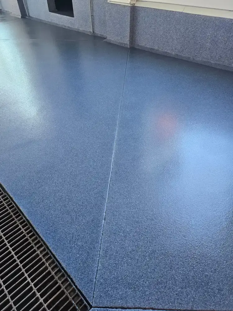 Glossy blue flake epoxy floor sloping to a floor drain in a car wash