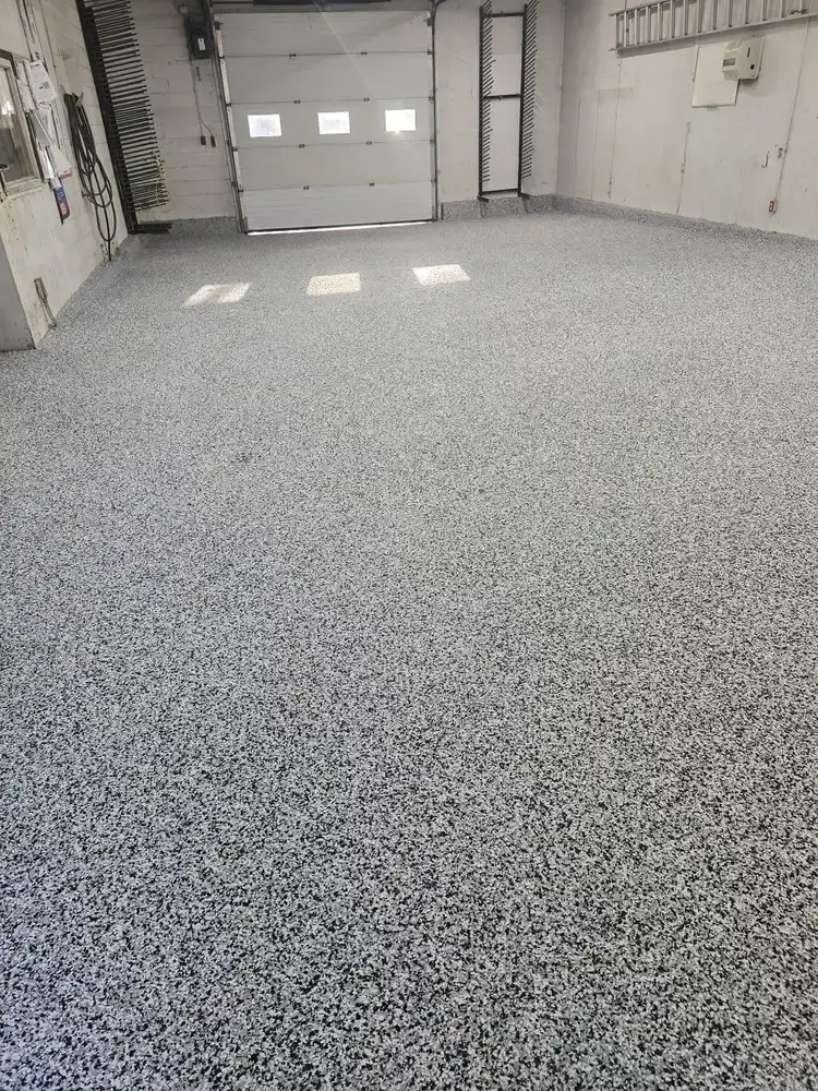 Grey flake epoxy floor across an empty garage bay