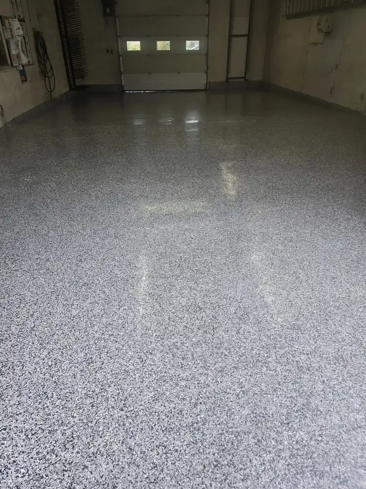 Glossy grey flake epoxy floor facing an overhead garage door