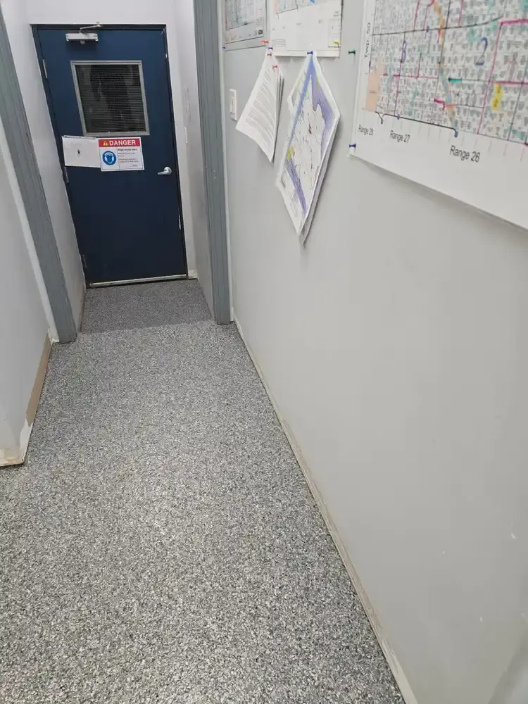 Grey flake epoxy floor in a narrow corridor leading to a steel door