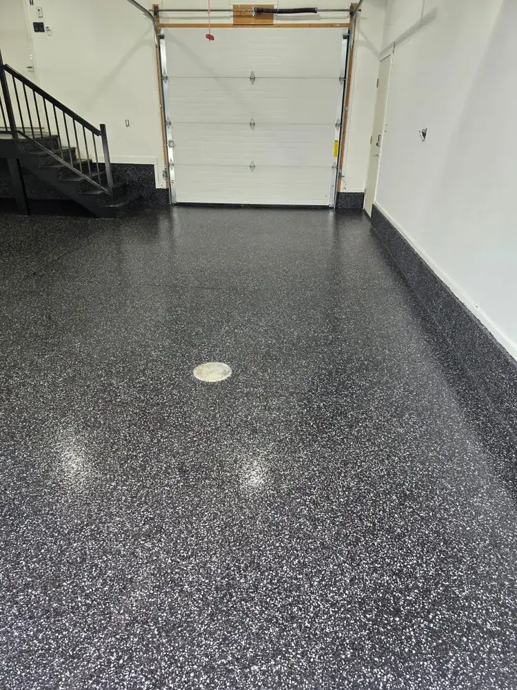 Raven flake epoxy floor leading to an open garage door