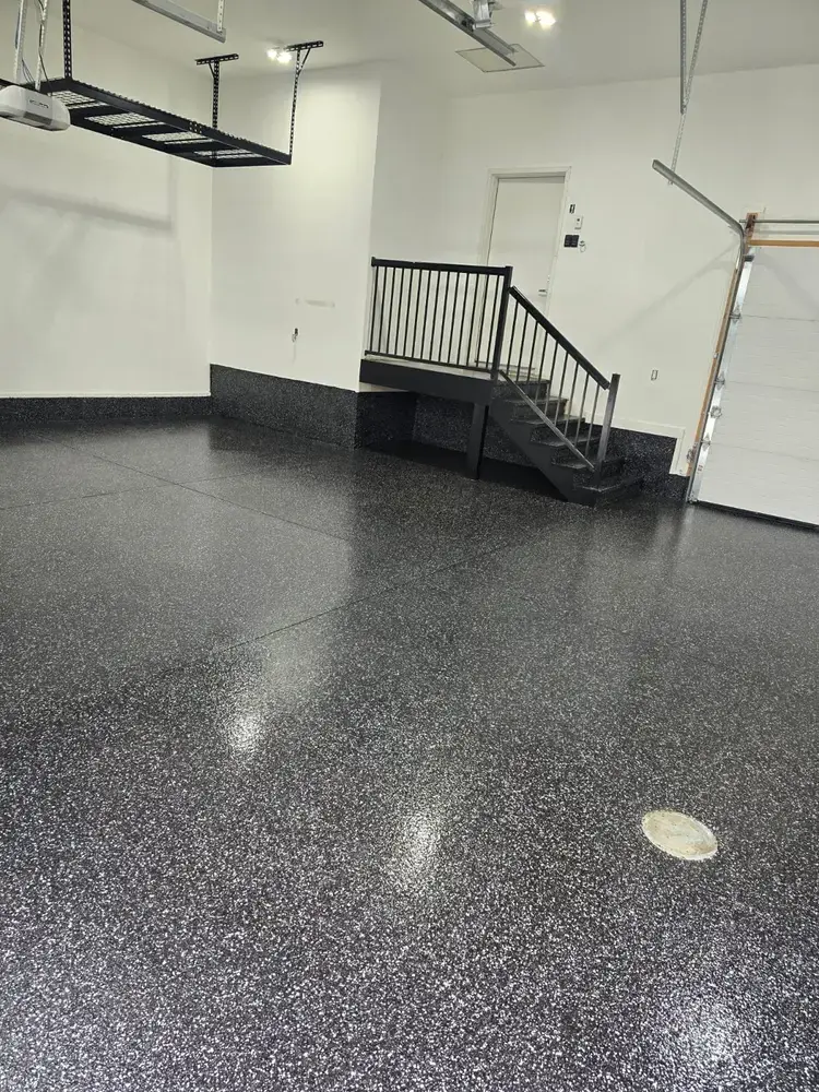 Raven flake epoxy garage floor beside finished wooden stairs