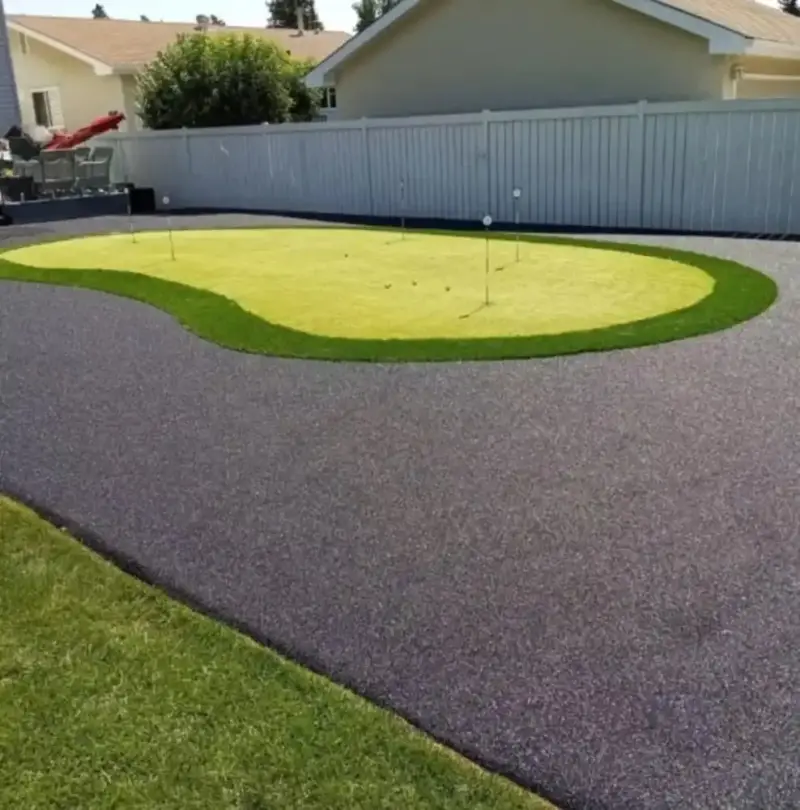 Rubber-paved backyard surface curving around a putting green