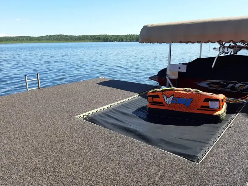 Rubber-surfaced dock beside a moored boat on a lake