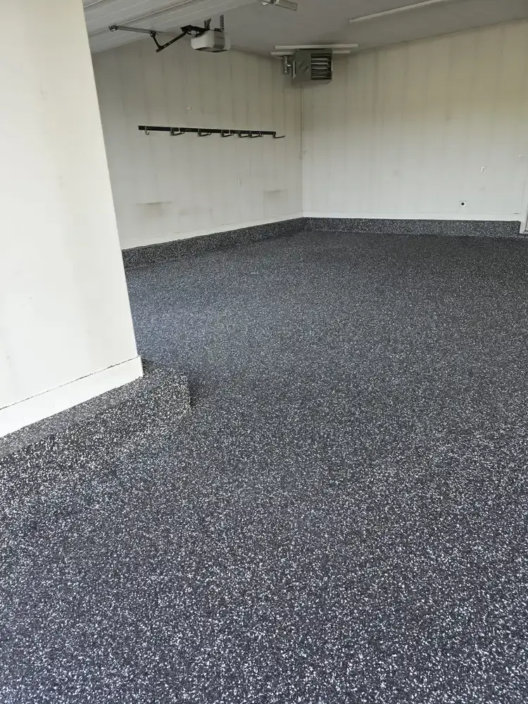 Dark speckled rubber surface in the corner of an empty garage