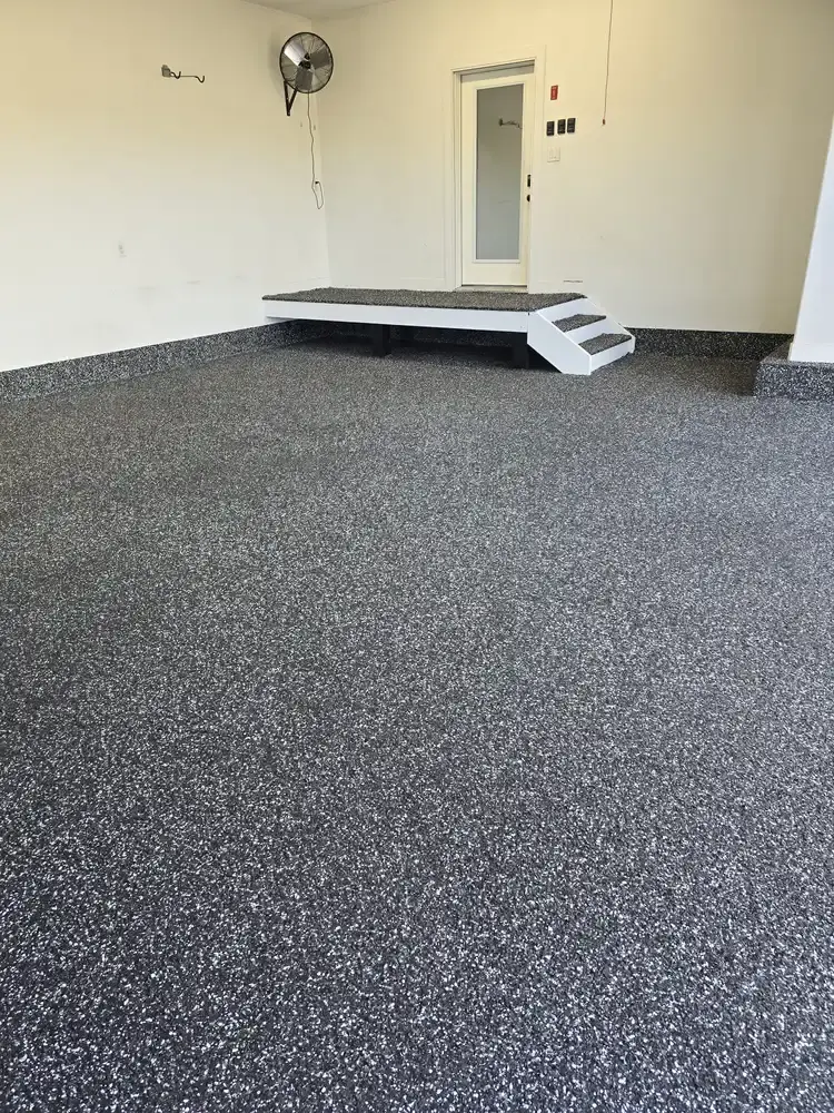Dark speckled rubber surface across a garage floor with entry steps