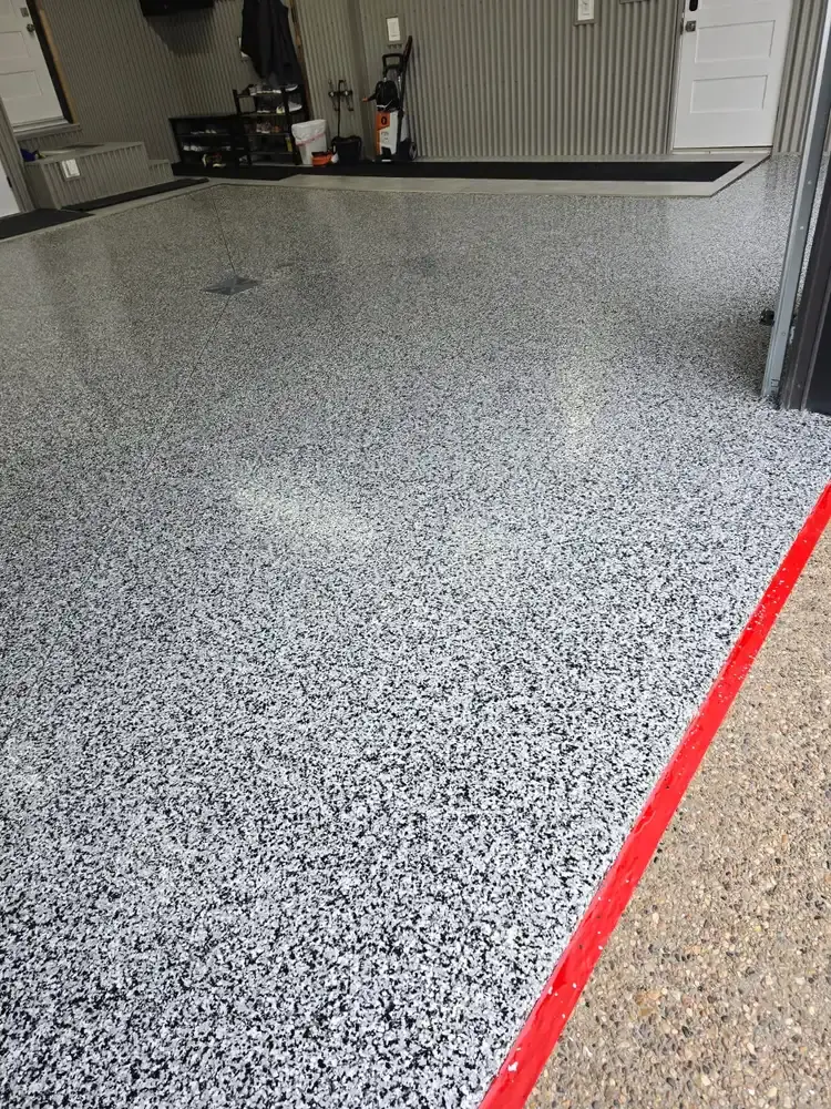 Black and white flake garage floor meeting the concrete apron