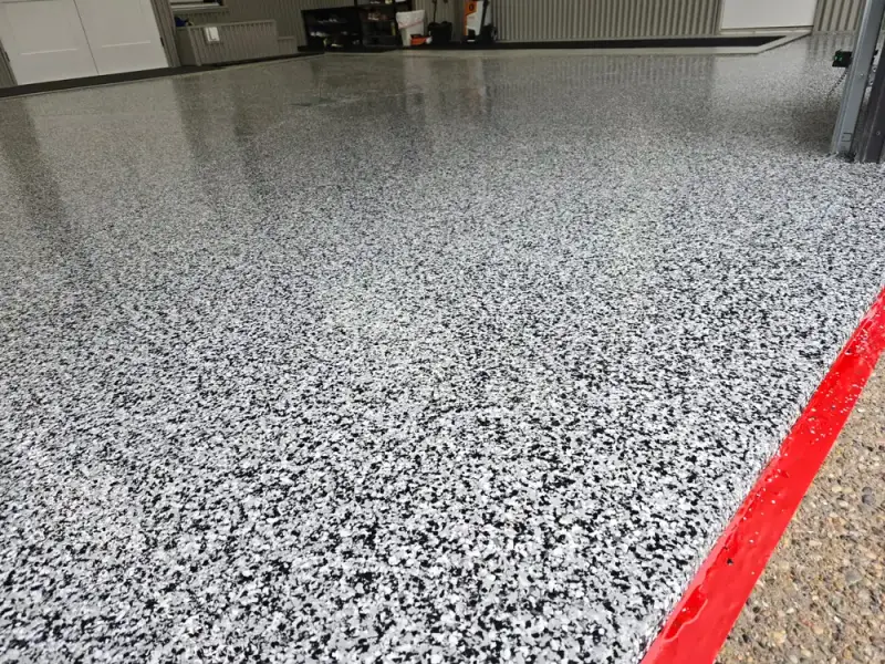 Black and white flake epoxy garage floor with a red edge line