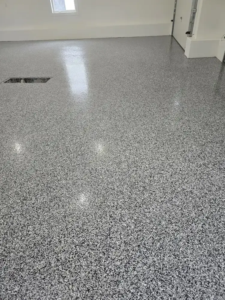 Speckled grey epoxy floor beside a garage work area